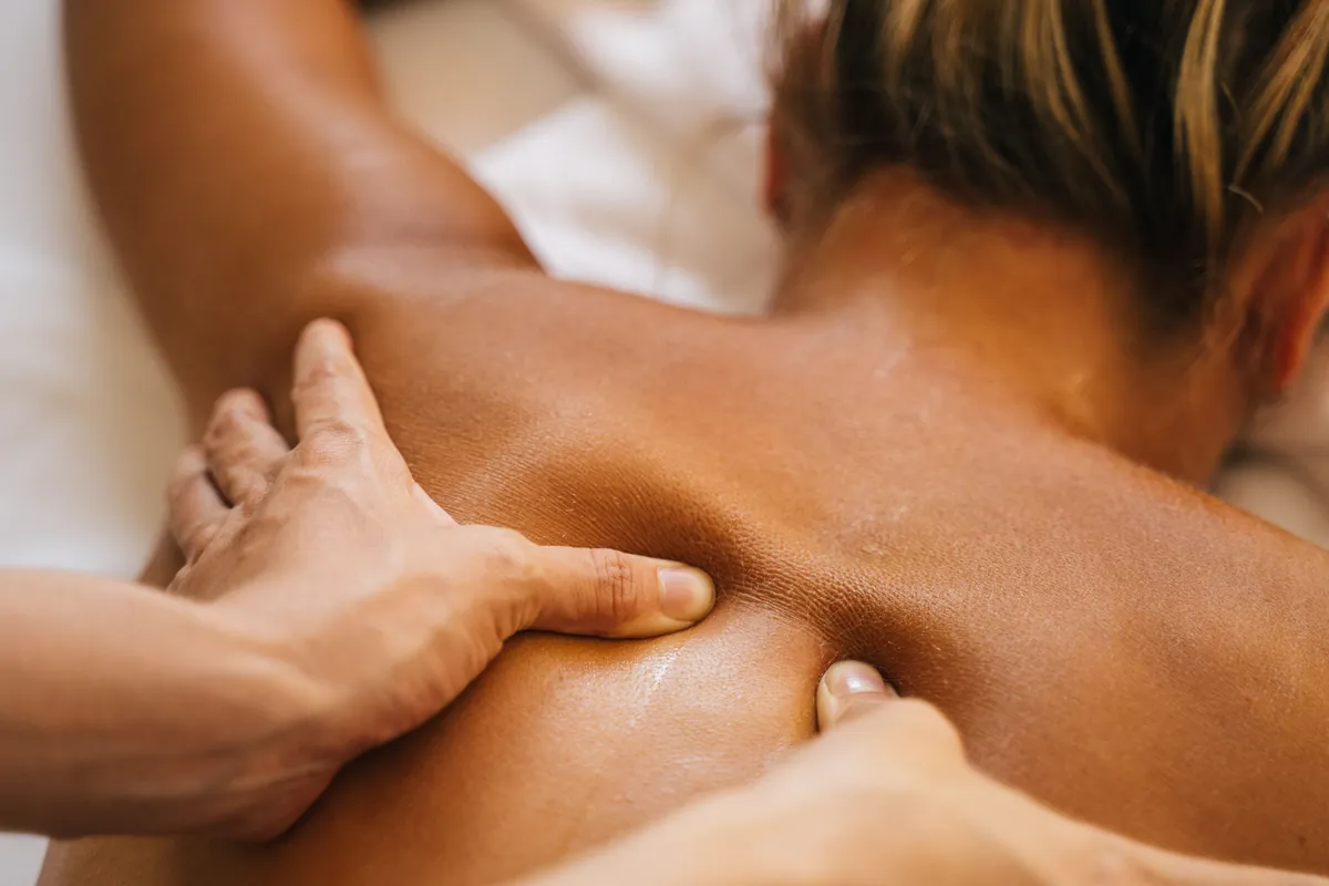 Firm thumb pressure along a client’s upper back during deep tissue massage in Salt Lake City